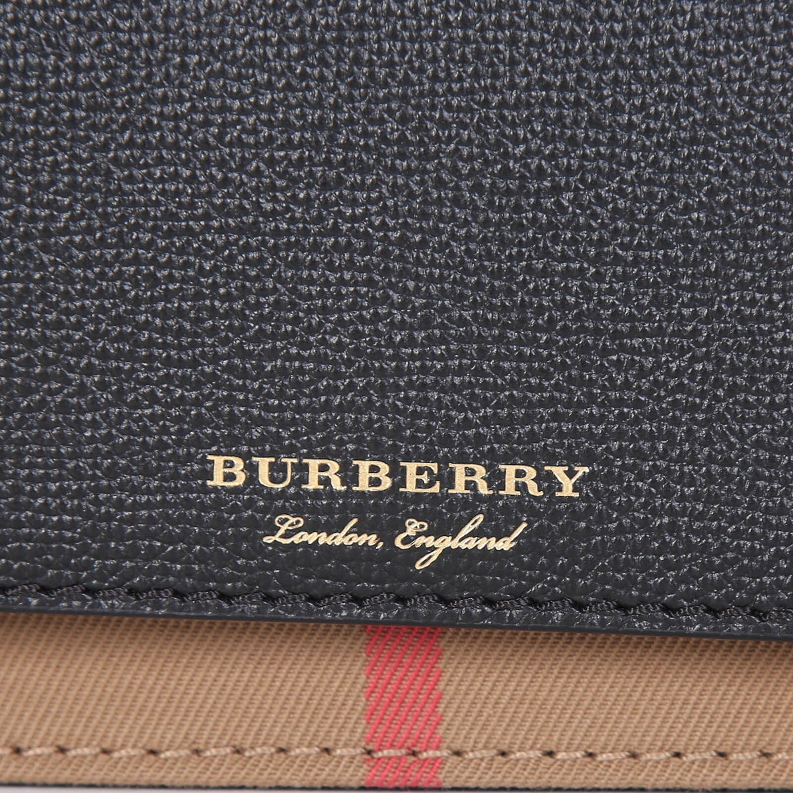 Close-up of Burberry crossbody bag black textured leather with gold logo and signature check pattern