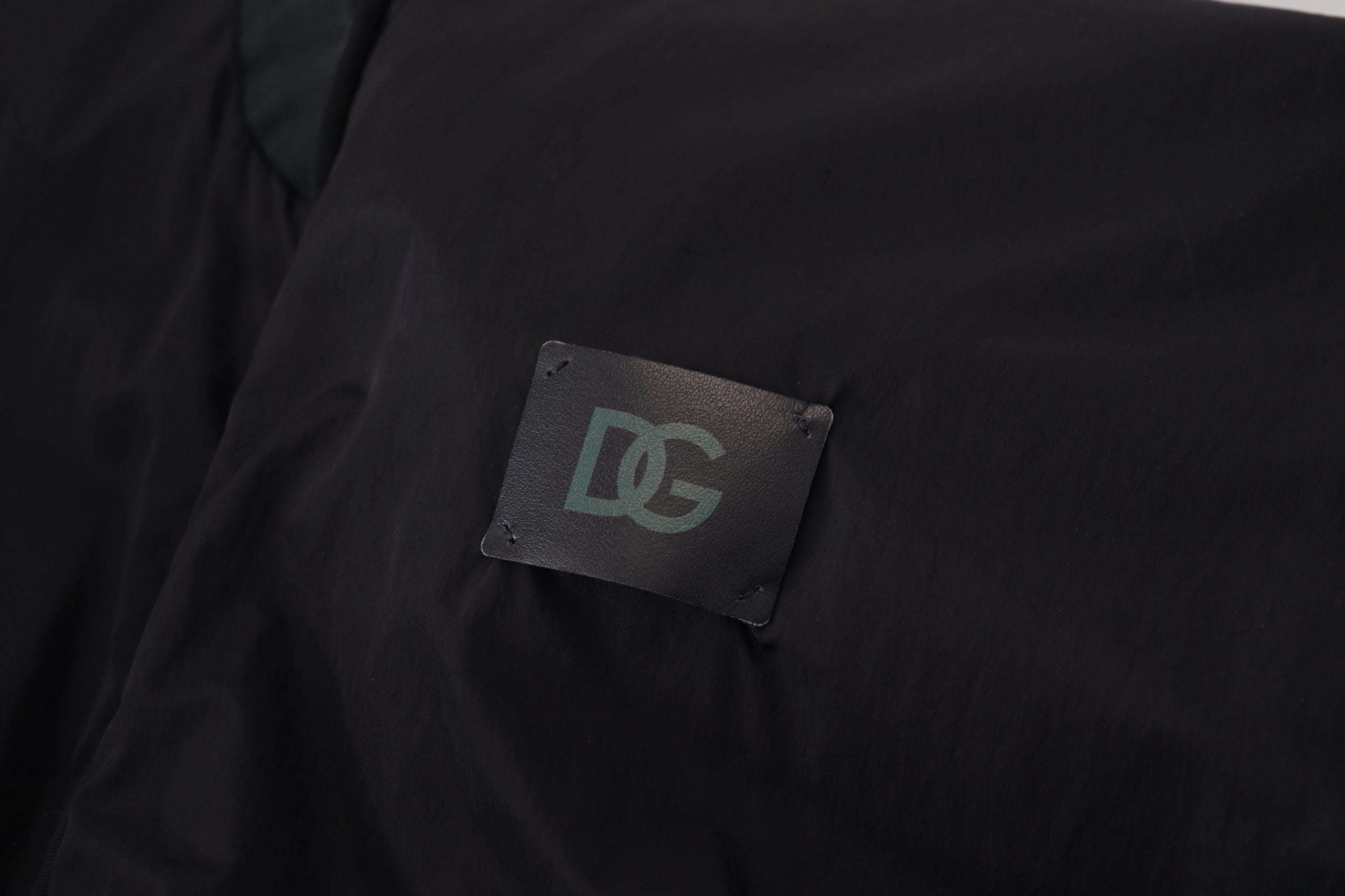 Close-up of Dolce & Gabbana black bomber jacket featuring DG logo patch on fabric